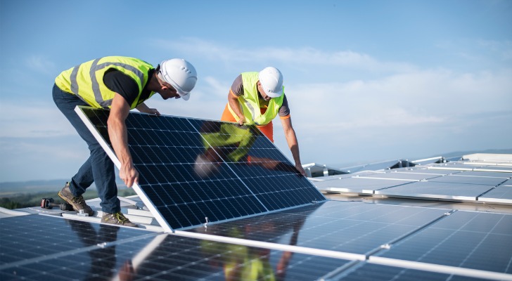 two-engineers-installing-solar-panels-on-roof